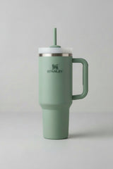 Green Stanley tumbler with handle and straw on a light background