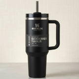 Black Stanley tumbler with handle and straw on a light background