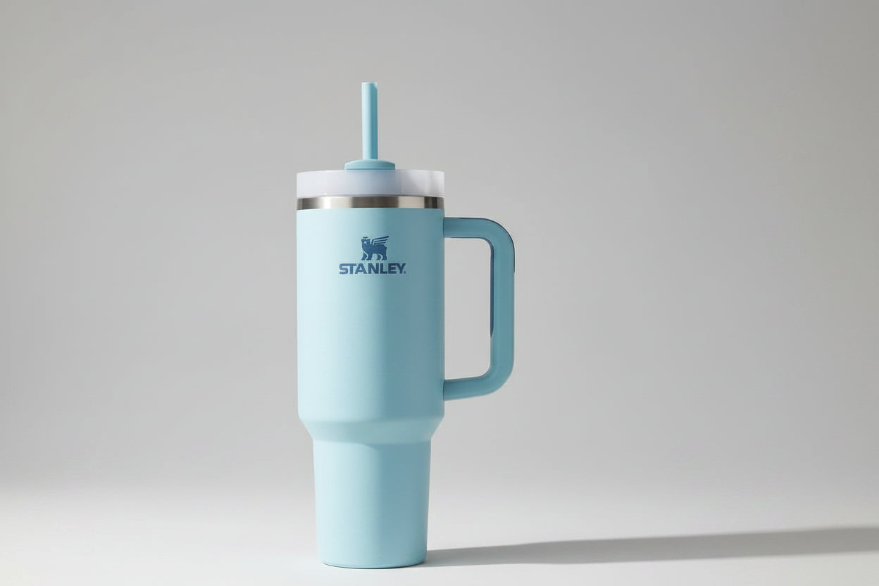 Light blue Stanley tumbler with handle and straw on a marble surface