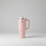 Pink Stanley tumbler with handle on a light beige background