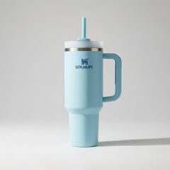 Light blue Stanley tumbler with handle and straw on a marble surface