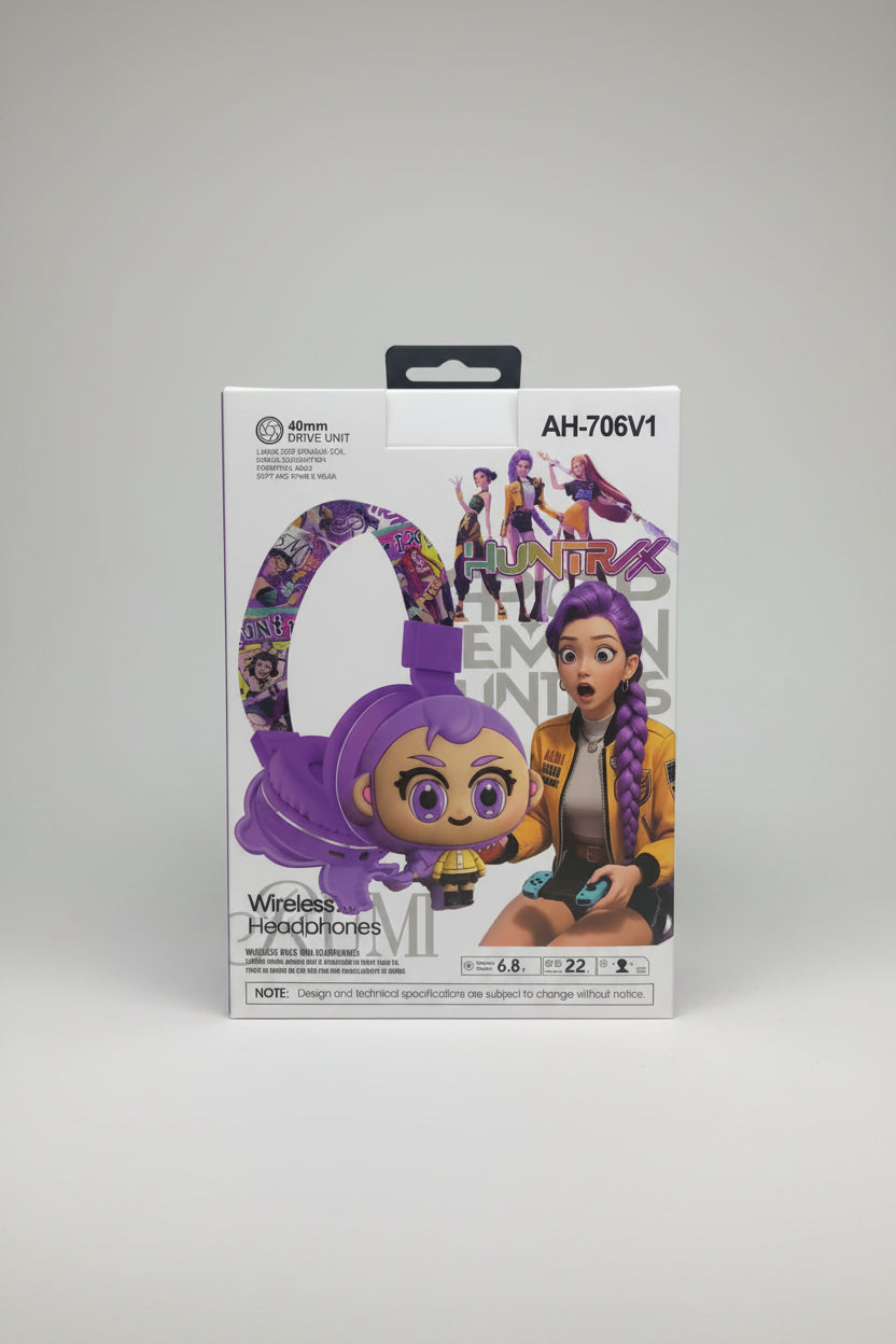 A hand holding a white retail box for a purple cartoon-style wireless headphones headset. The box features the text 'AH-706V1' and 'Wireless Headphones' with illustrations of the product and the character Emily from The Dream Team.