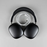 Black headphones with a cable in an open white box on a wooden surface