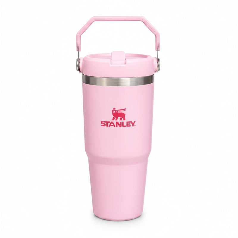 A light pink Stanley travel tumbler with a matching pink lid and carry handle, featuring a silver stainless steel band and the red Stanley logo on the front, set against a plain white background.